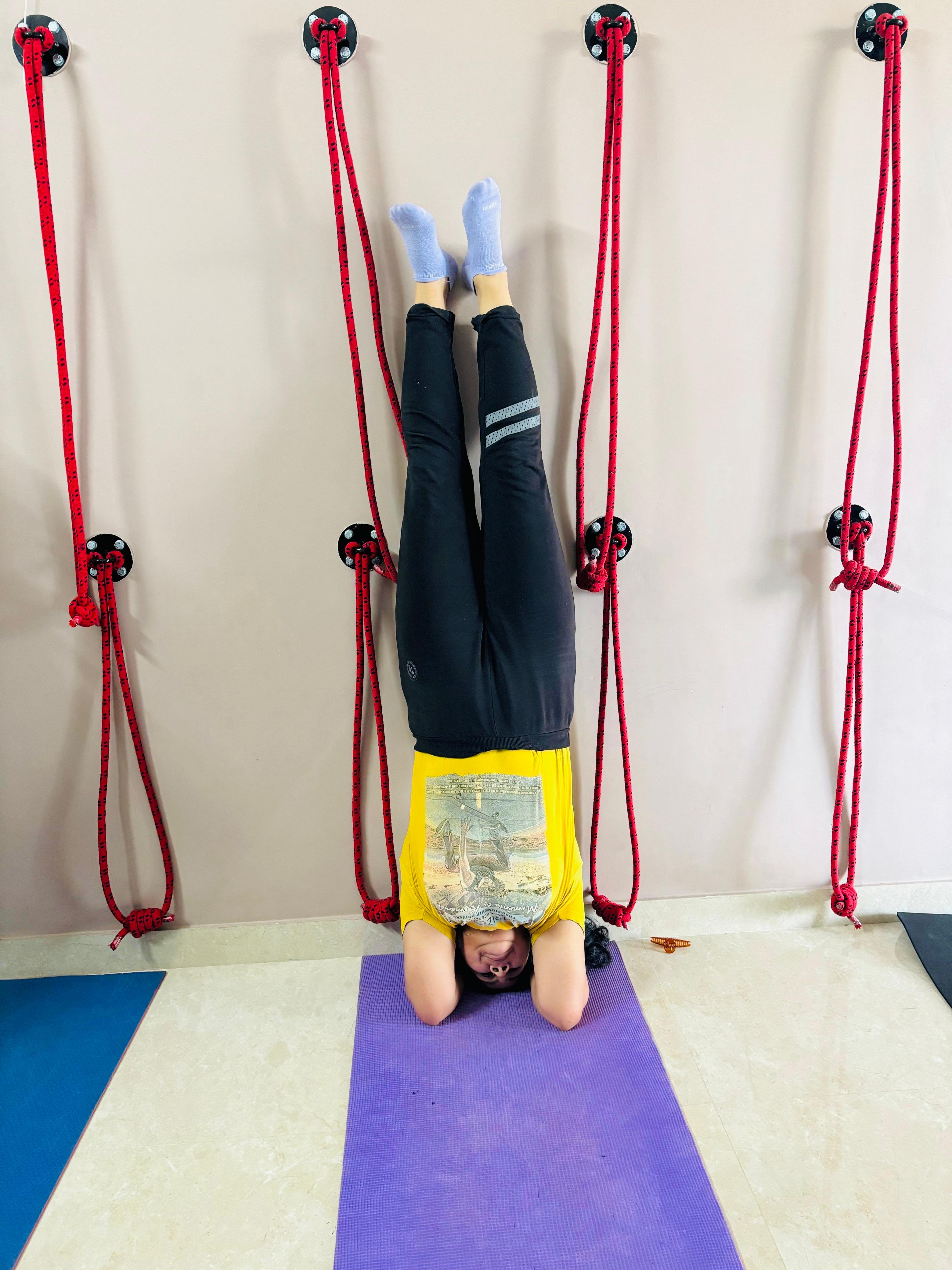 Riya performing a wall-supported inversion yoga pose during a flexibility session at Attmashuddhi