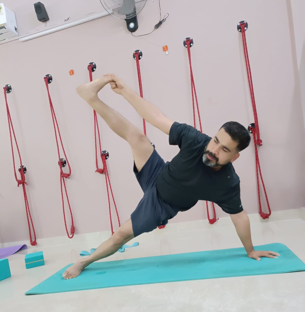Ravi practicing balance, flexibility, and core strength through an advanced yoga posture at Attmashuddhi